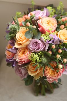 a bouquet of colorful flowers sitting on top of a table next to a white vase