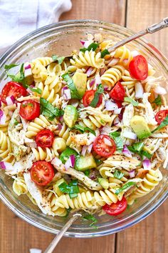 a glass bowl filled with pasta salad on top of a wooden table