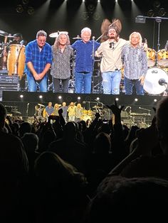 a group of people standing on top of a stage next to each other in front of a crowd