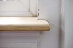 a close up of a window sill with wood on the edge and white paint