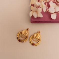 Description: Step into minimal sophistication with our exquisite antique gold-plated Chandbali earrings. Delicately adorned red kempu stones accentuating the Lakshmi temple coin, it exudes timeless allure and sophistication in every detail. Perfect for enhancing any ensemble, these earrings effortlessly harmonize with other antique jewelry for a refined and coordinated look. Details & Specification: Materials used: Brass Alloy with Antique Gold Plating Weight - 10.2 gm Length - 3.5 cm Make it cu Kasu Chandbali Earrings Gold, Lakshmi Design Gold Earrings, One Stone Earrings Gold, 2 Gm Gold Earrings, Kasu Earrings Gold, Chandbali Earrings Gold Antiques, New Earrings Designs Gold, Trending Gold Earrings, Stud Designs Gold