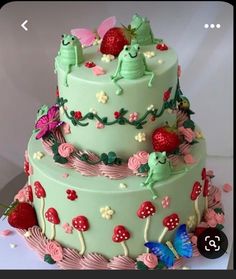 a three tiered cake with strawberrys and butterflies on the top is decorated in pastel green frosting