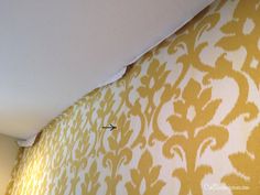 the corner of a room with yellow and white wallpaper