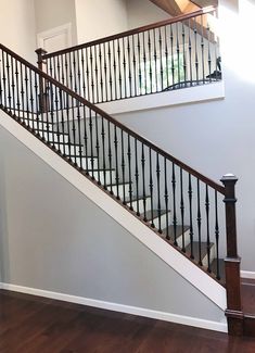 a stair case in a house with wood floors and railings on both sides, leading to the second floor