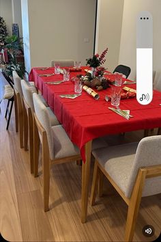 a long table with red cloths and place settings on it in front of a christmas tree