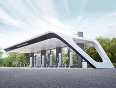 a futuristic gas station sits on the side of an empty road with trees in the background