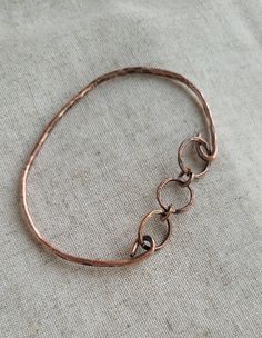 "Hand forged 12-gauge copper wire shaped and hammered into a beautiful bangle bracelet with three copper links adding interest and detail.    I've oxidized and polished to bring out the natural beauty of the copper. I can add a clear coating to prevent further oxidation if you would like. Care Instructions: - Remove your jewelry before showering, sleeping, swimming or sweating. - Most pieces, unless otherwise specified, can be cleaned with a mild dish soap and soft toothbrush  if really necessary. Do NOT soak your jewelry or use any chemicals. - Clean your jewelry before and after each use with a soft dry polishing cloth.  >Please keep in mind when ordering that color settings on your  screen and lighting in product photography vary so the product might  differ a tad from what you see on s Hammered Bronze Metal Bracelets, Bronze Hammered Metal Bracelets, Carrot Jewelry, Bracelet Photography, Hammered Wire Jewelry, Copper Wire Bracelet, Hand Forged Jewelry, Hammered Copper Earrings, Matching Couple Bracelets