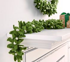 a green wreath is sitting on top of a white mantle