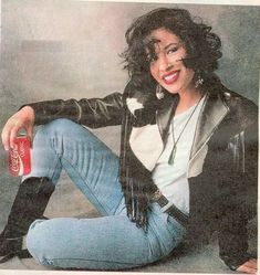 a woman sitting on the ground with a soda in her hand and wearing black boots