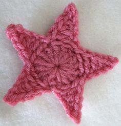 a pink crocheted star is laying on a white surface