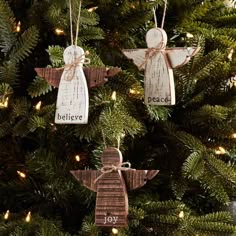 two wooden angel ornaments hanging from a christmas tree with the words believe, peace and joy