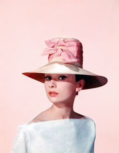 a woman wearing a hat with a pink bow on it's brimmed top