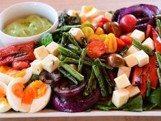 a salad with eggs, tomatoes, green beans and other veggies on it