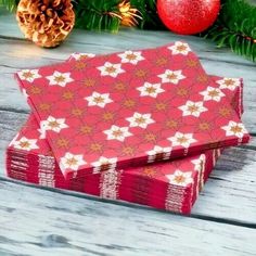 three red and white christmas wrappings sitting on top of a wooden table next to pine cones