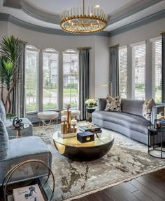 a living room filled with furniture and windows covered in shades of gray, gold and white