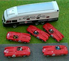 four red toy cars sitting next to each other on a green mat in front of a white truck