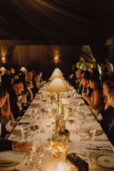 a group of people sitting at a long table with plates and wine glasses on it