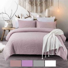 a bed covered in a pink comforter and pillows