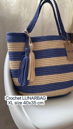 a blue and white striped purse with tassels on the handles, hanging from a hook