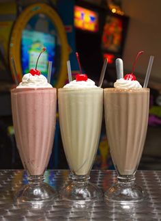 three different kinds of milkshakes on a table