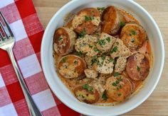 a white bowl filled with meat and potatoes on top of a red checkered table cloth