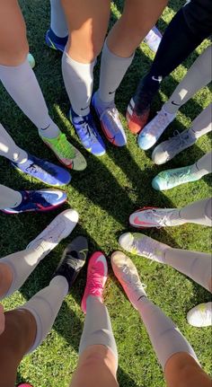 a group of people standing in a circle on top of grass with their feet together