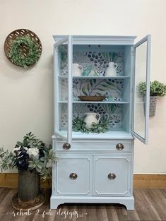 a blue china cabinet with plants in the corner