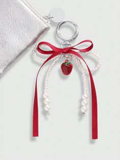 an apple charm is attached to a red ribbon with pearls and a bow around it