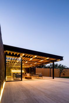 an outdoor living area is lit up at night with lights on the ceiling and wooden flooring