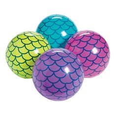 three different colored balls sitting next to each other on a white surface with fish scales