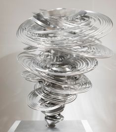 a metal object with many spirals on it's base in front of a white wall