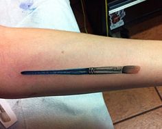 a person with a tattoo on their arm holding a paintbrush