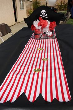 a table topped with a red and white striped cloth covered tablecloth next to a pirate hat