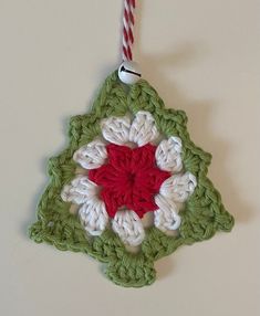 a crocheted ornament hanging on a wall with a red and white stripe