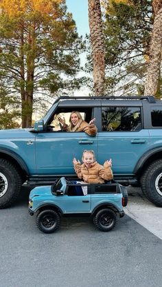 two children are sitting in the back of a blue jeep with an image of a boy on it