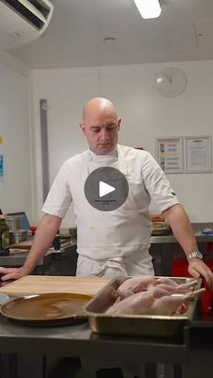 a man standing in front of a pan filled with meat on top of a table