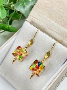 "Little art pieces, dangle from your ears as you wear these phenomenal Murano Glass earrings! These glass beads are hand created by reknowned artisans from Murano, Italy that use ancient methods and techniques to make the most amazingly colorful glass you can imagine. Each 11mm cube earring is adorned with genuine 14k gold foil with an array of colored glass pieces within. Each glass bead is unique and special. The earrings hang 1.5 inches on hammered gold Vermeil ear wires. These will quickly b Modern Glass Earrings For Gifts, Glass Drop Earrings For Gift, Modern Glass Jewelry With Ear Wire, Elegant Hypoallergenic Glass Jewelry, Modern Gold Glass Earrings, Elegant Nickel-free Glass Earrings, Elegant Nickel Free Glass Earrings, Unique Gold Glass Earrings, Elegant Hypoallergenic Glass Earrings