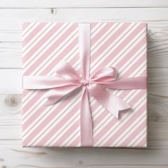 a pink and white striped gift box with a bow