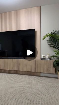 a flat screen tv sitting on top of a wooden entertainment center next to a plant