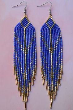 blue and gold beaded earrings on a pink background