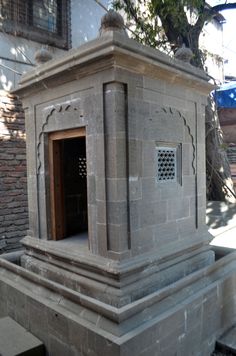 an outdoor shrine in front of a brick building with a door and window on the side