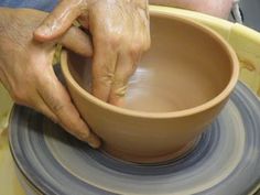 a person is making a bowl on a potter's wheel with one hand and the other