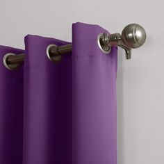 purple curtains hanging on the side of a white wall with a metal curtain rod in front of them