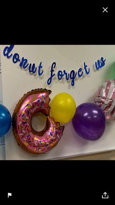 there are balloons and donuts hanging on the wall next to a sign that says, donut forget us