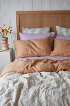 an unmade bed with two vases and flowers on the nightstand next to it