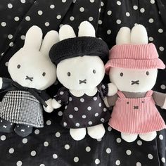 three stuffed animals are sitting next to each other on a black and white polka dot blanket