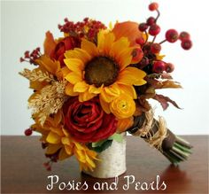 a bouquet of sunflowers and other flowers in a white vase on a table