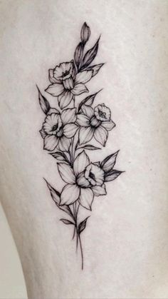 a black and white photo of flowers on the back of a woman's thigh