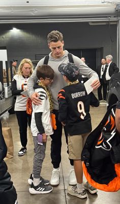 a group of people standing around each other in front of a man wearing a jersey