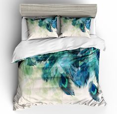 an image of a bed with blue feathers on it's comforter and pillows